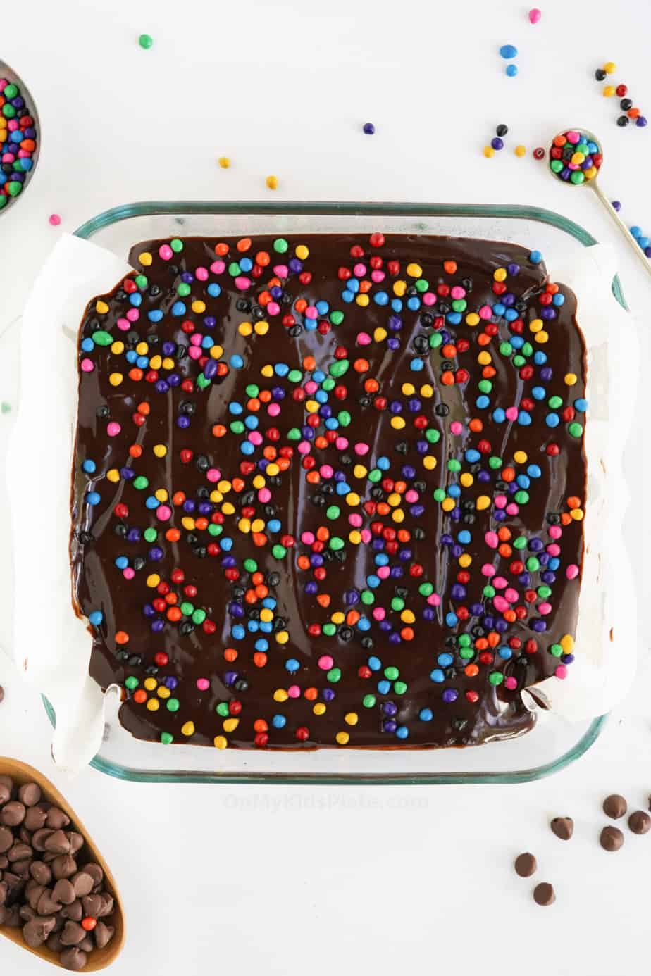 Chocolate brownies in the pan from overhead covered in chocolate frosting and rainbow crunch sprinkles.