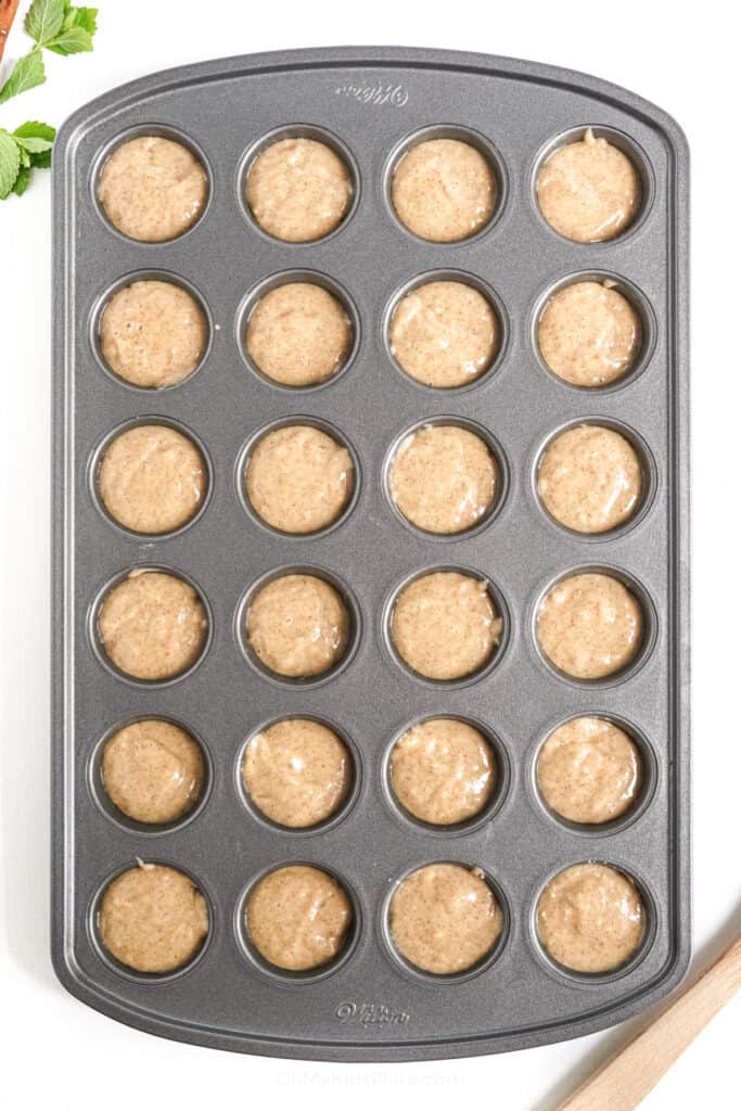 Mini muffin pan full of apple cider donut batter.