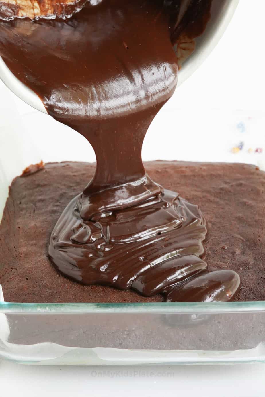 Pouring ganache  frosting over chocolate brownies in the pan from the side