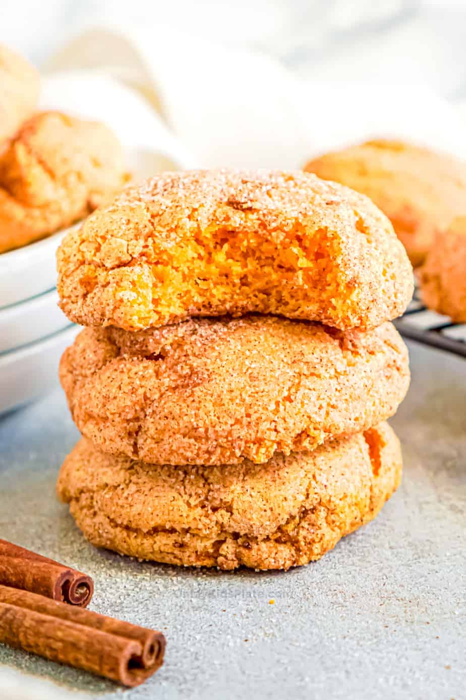 pumpkin snickerdoodle cookies stacked with a bite taken from the top cookie