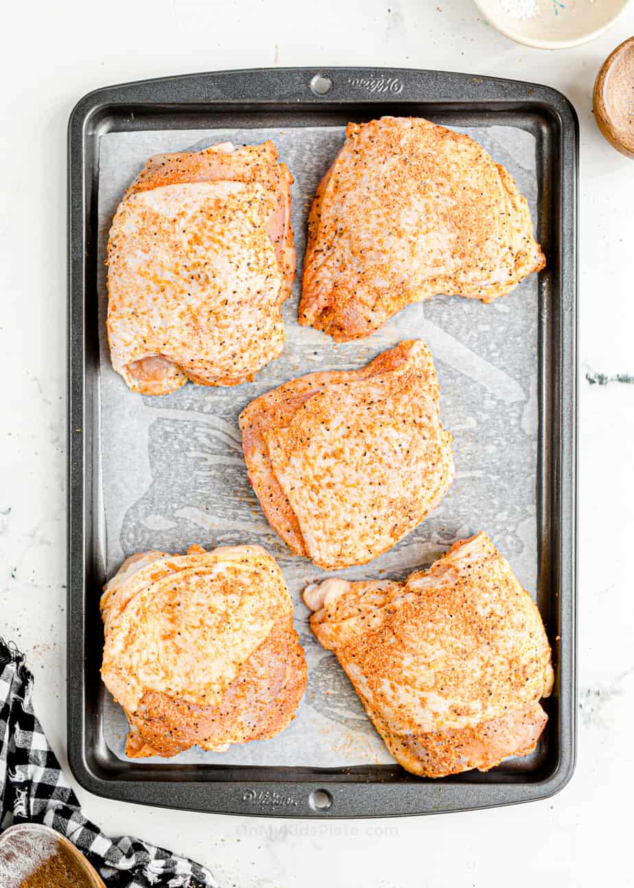 Chicken thighs with spices on pan before baking