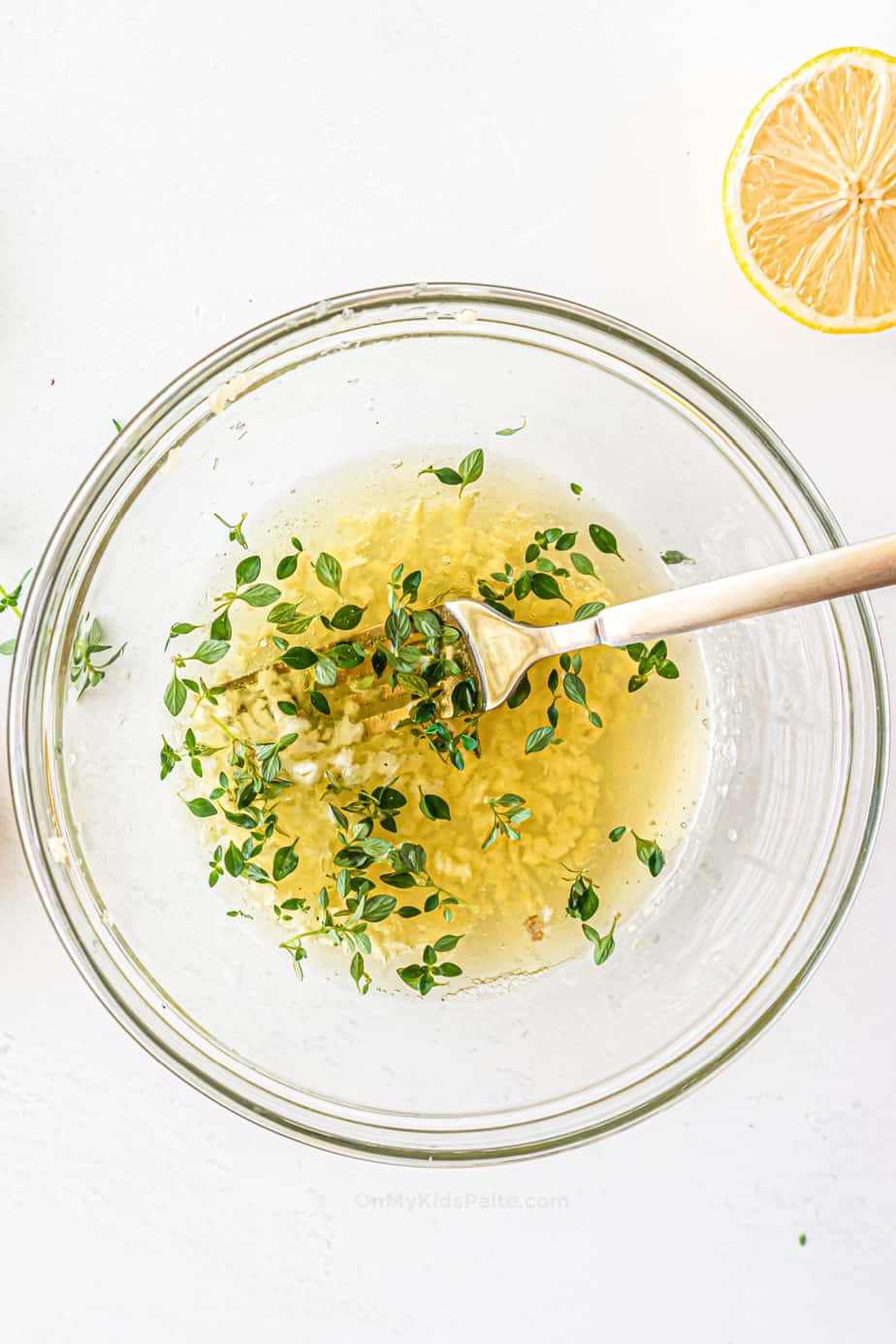 Mixing lemon juice, garlic, olive oil, and spices for marinade in a large glass bowl.