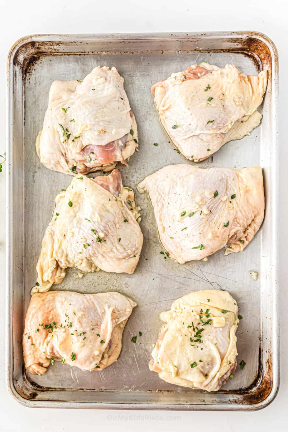 Raw chicken thighs with herbs on pan