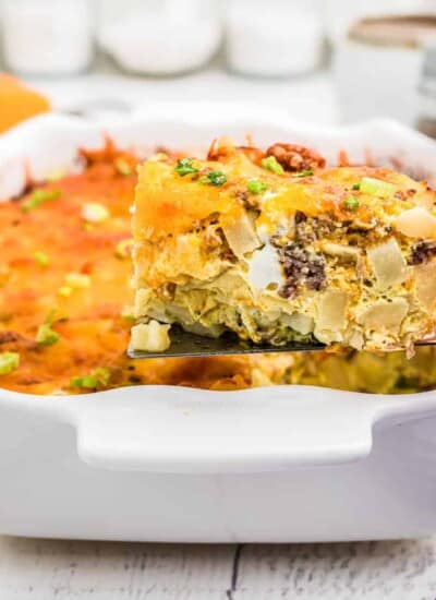Slice of breakfast casserole being lifted from the pan with a spatula from the side.