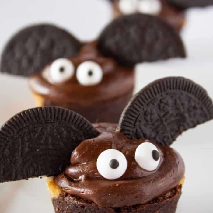 Brownie bite decorated to look like a bat with frosting and Oreo cookies