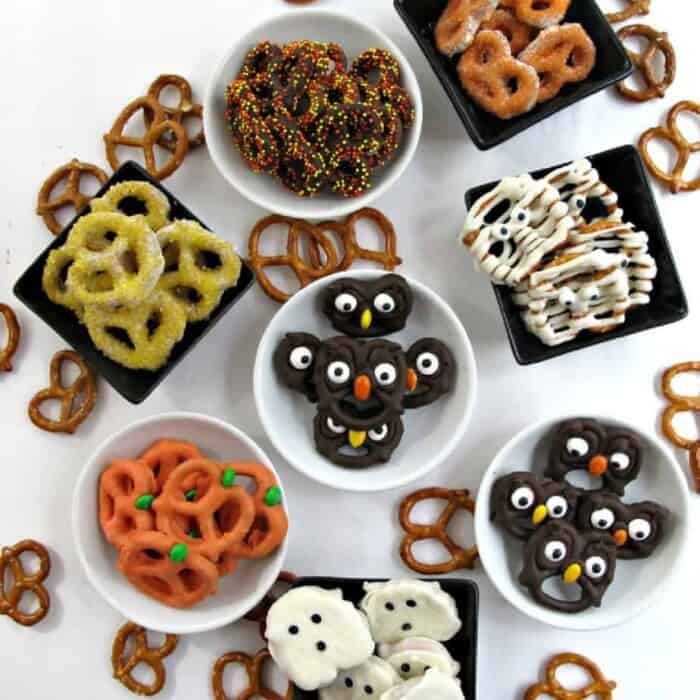 A variety of chocolate dipped pretzels in bowls decorated like owls, mummies, pumpkins, ghosts and with sprinkles
