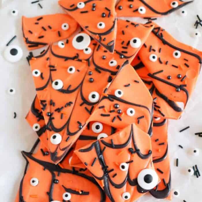 Orange chocolate pieces covered in sprinkles, candy eyes and chocolate spider web decorations