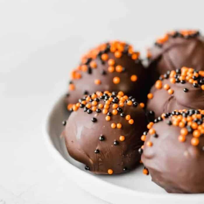 Chocolate Oreo truffles on a plate from the side decorated with Halloween sprinkles
