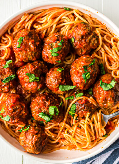 Meatballs in pasta sauce over top of spaghetti in a bowl