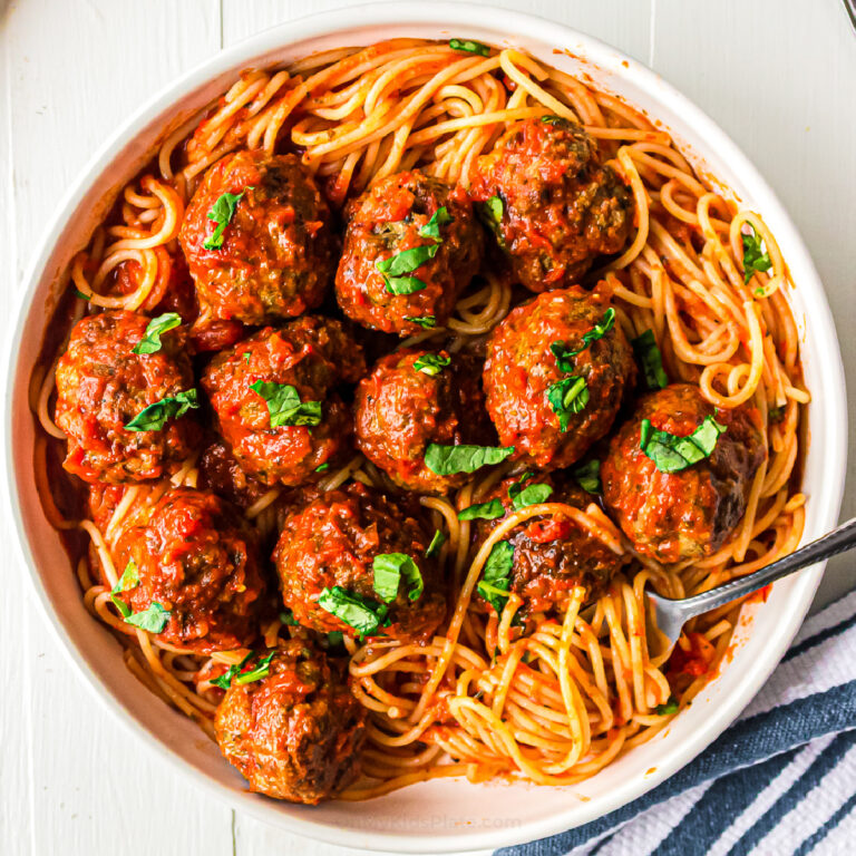 Meatballs in pasta sauce over top of spaghetti in a bowl