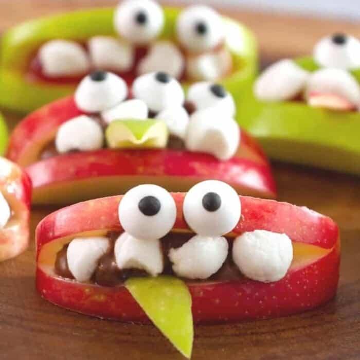 Apple slices decorated with marshmallows and candy eyes to make a monster face