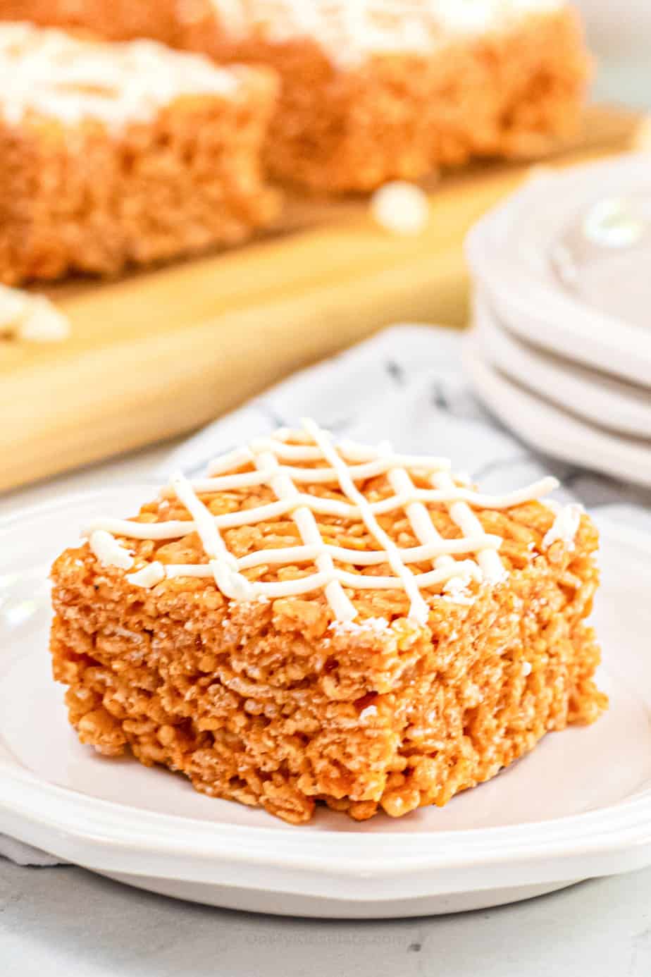 Pumpkin rice krispie treat drizzled with white chocolate on a plate up close