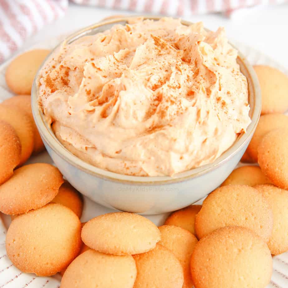 Close up of light orange pumpkin dip on a plate with vanilla cookies