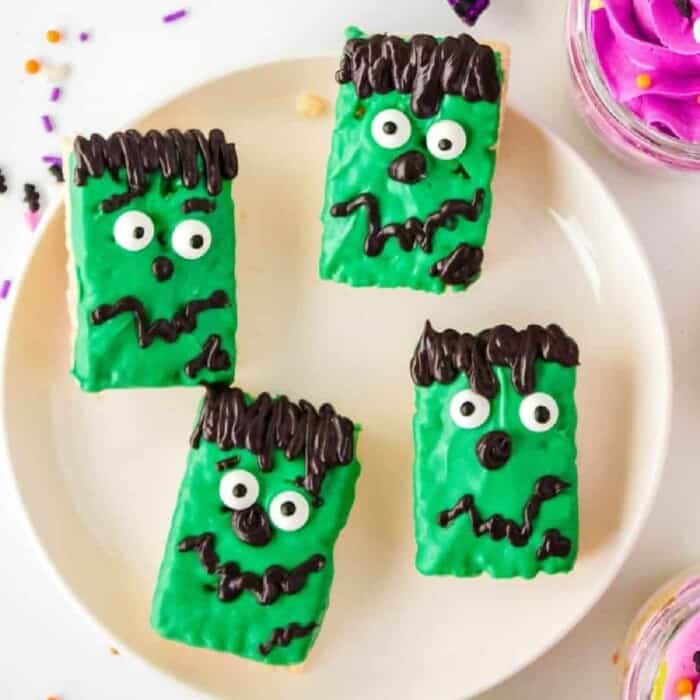 Rectangle rice krispie treats decorated like green Frankenstein monsters on a plate.