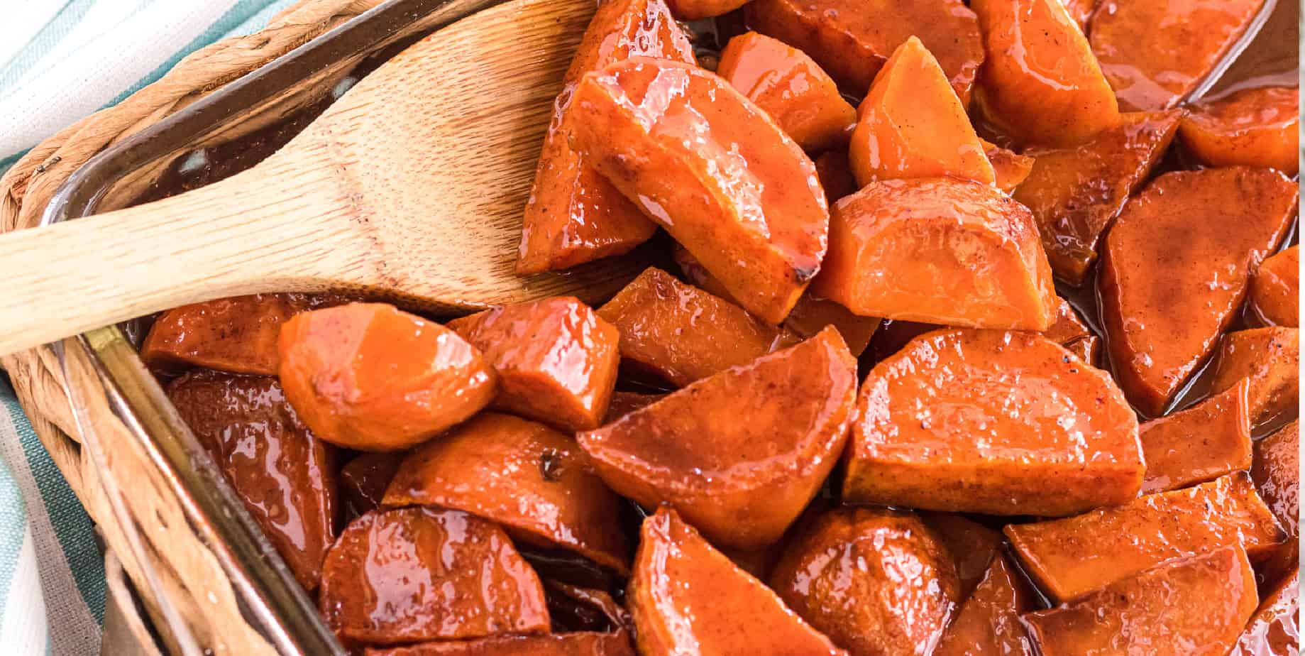 Candied yams wide view in a baking dish with a spoon scooping