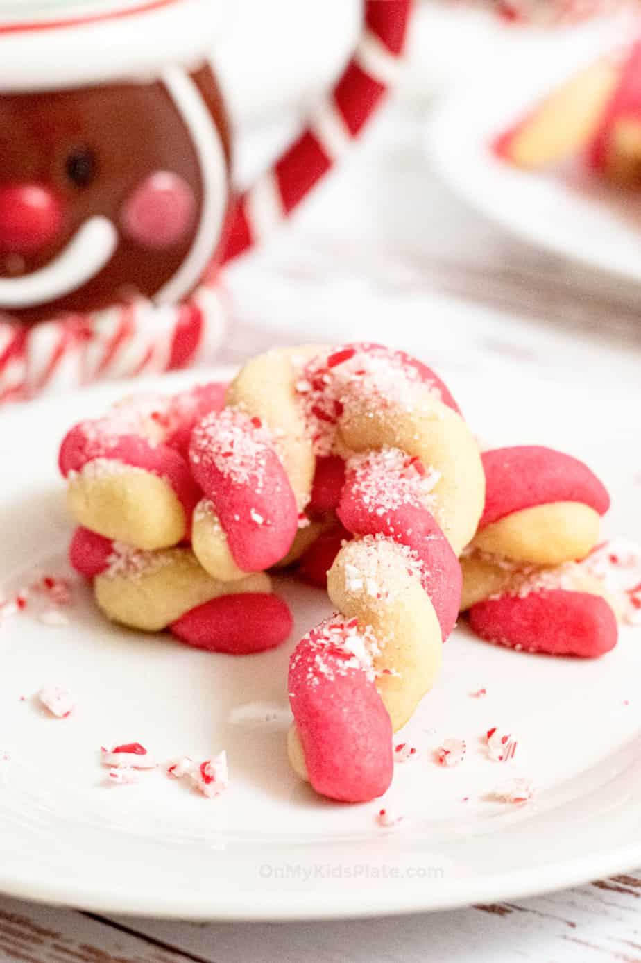 Twisted red and white sugar cookie on a plate shaped into a candy cane.