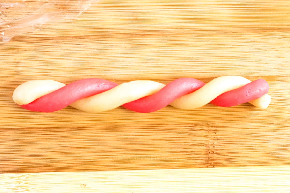White and red cookie dough twisted into a rope on a cutting board