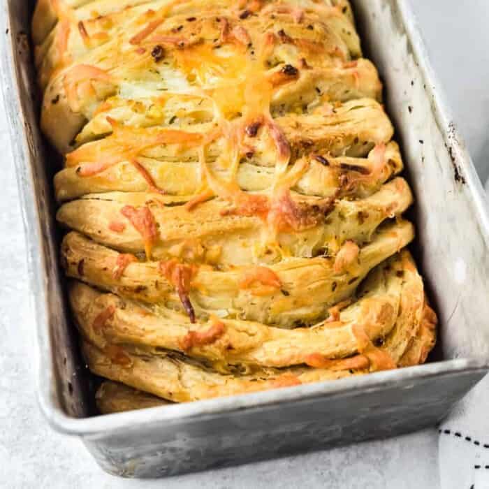 Cheesy bread in loaf pan tilted zoomed in on end of pan