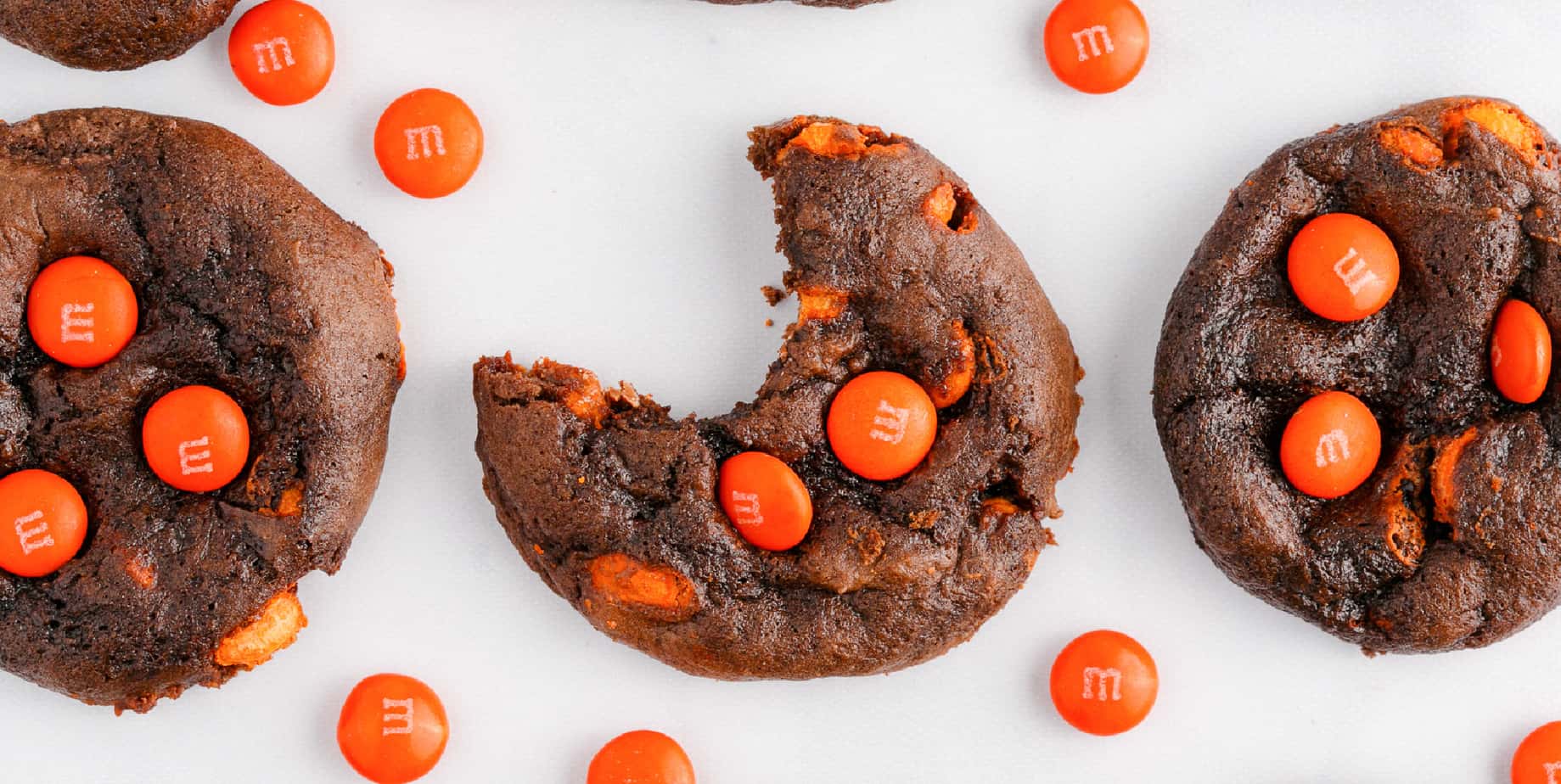 chocolate cookies with range candies on a table close up, one missing a bite