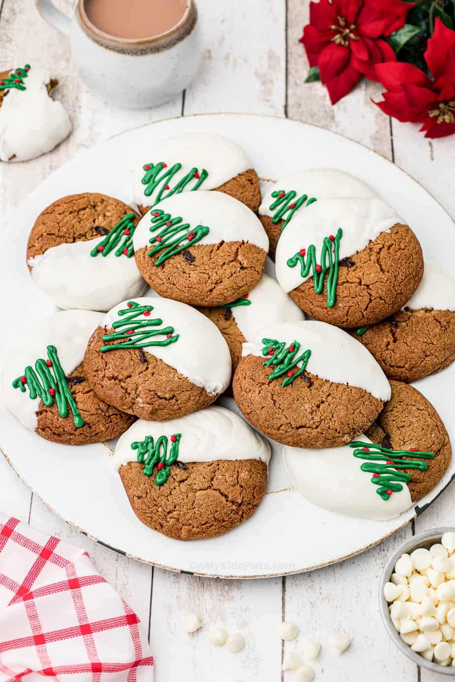 Plate of molasses cookies decorated dipped in white chocolate and decorated with Christmas trees.