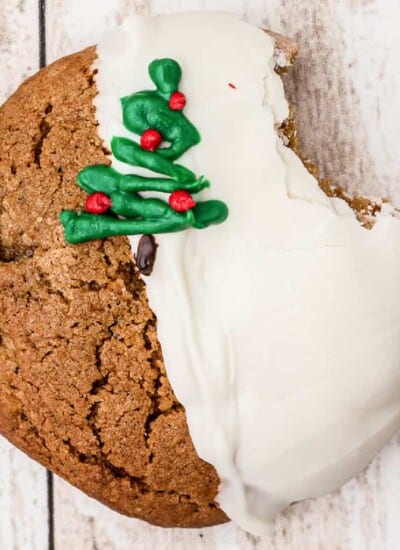 Close up of a molasses cookie dipped in white chocolate and decorated with a chocolate Christmas tree.
