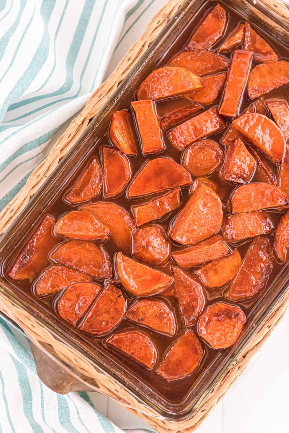 Cooked glazed yams in a brown sauce in a baking dish from overhead