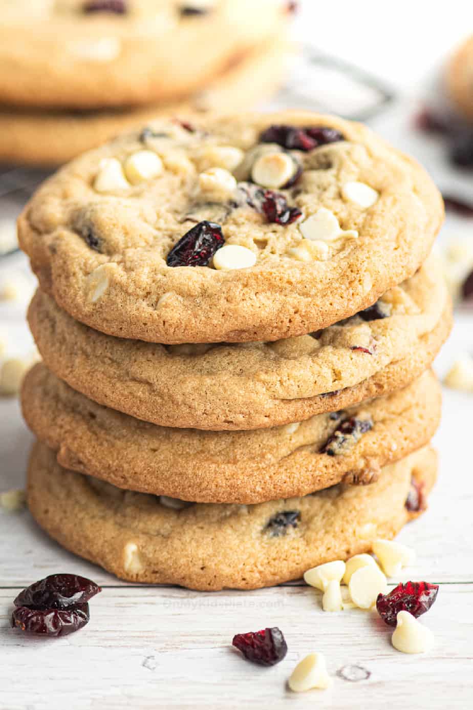 Super close up of four stacked white chocolate chip cranberry cookies from the side