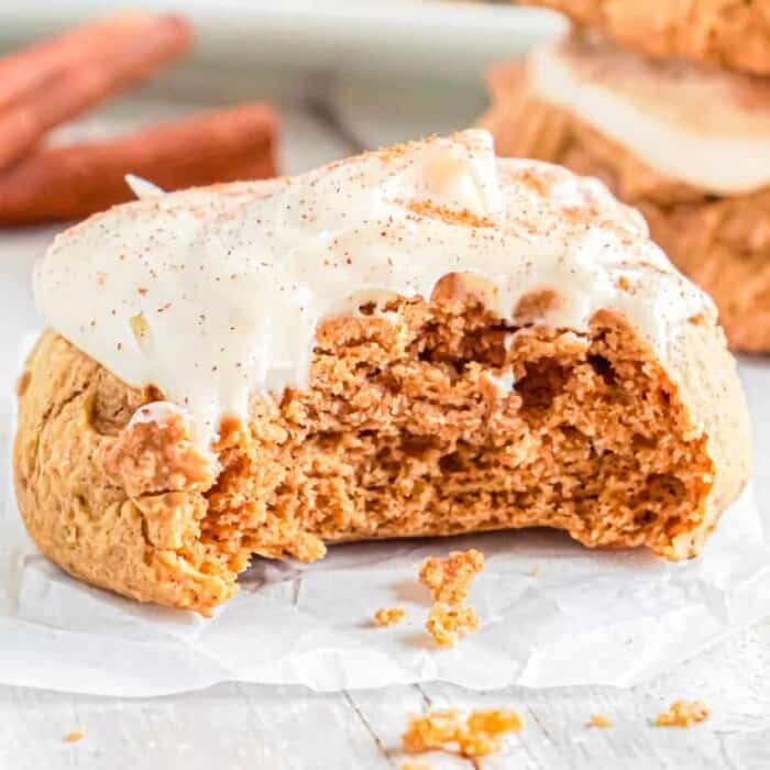Up close view of a pumpkin cookie with frosting with a bite missing
