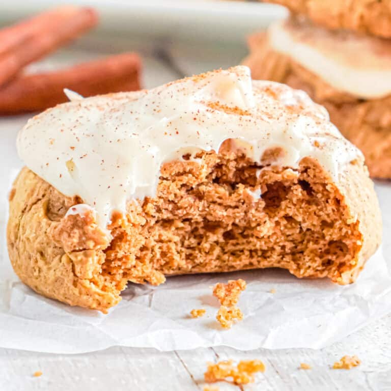 Up close view of a pumpkin cookie with frosting with a bite missing