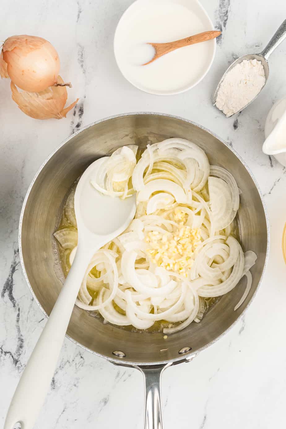 Onion and garlic cooking in a pan with a spoon stirring