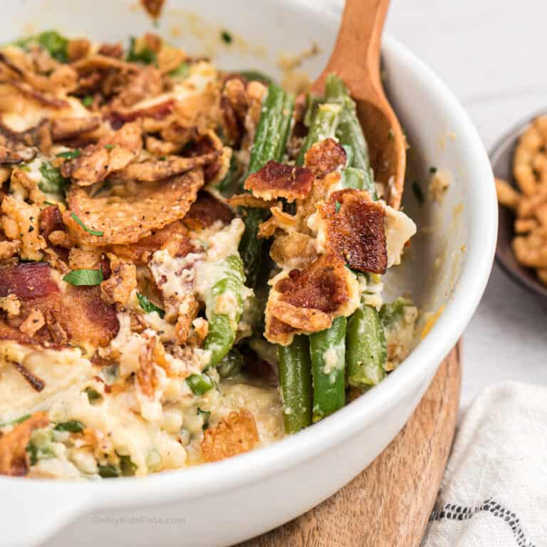 Close up of spoon scooping green bean casserole with bacon from a casserole dish