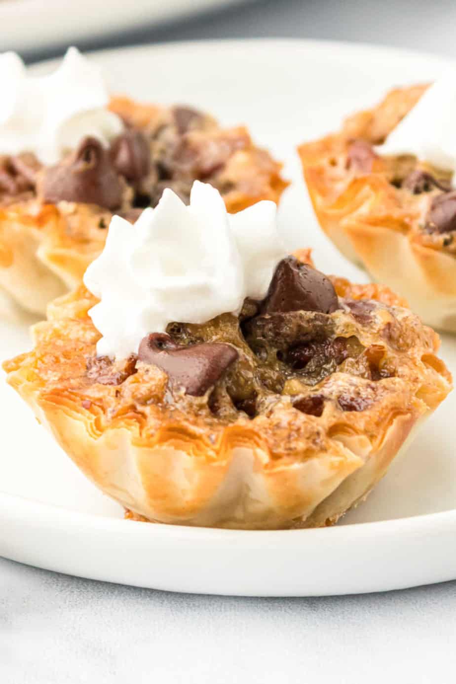 Mini pecan chocolate pie bites topped with whipped cream close up