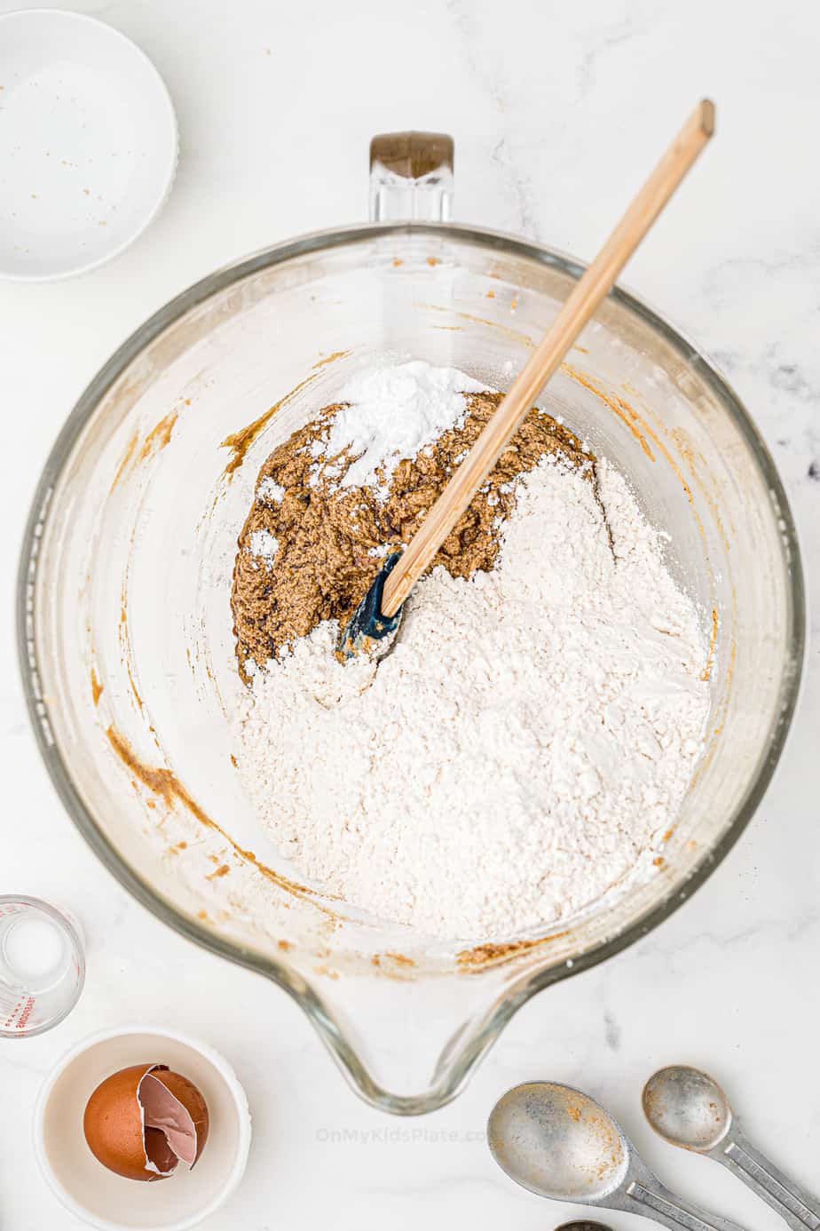 Mixing dry flour and other cookie ingredients into wet ingredients in a large mixing bowl from overhead