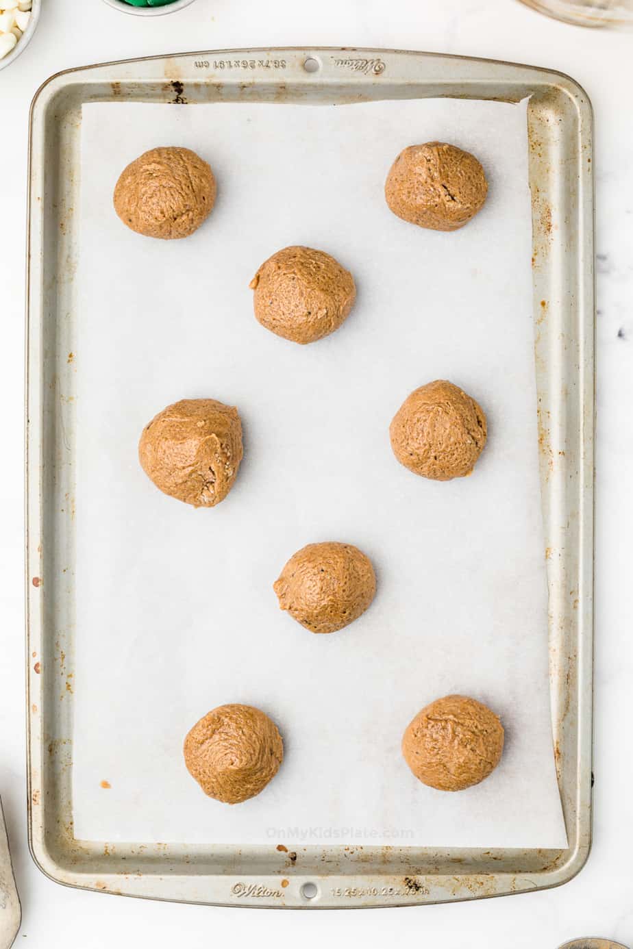 Molasses cookie dough on a cookie sheet lined with parchment paper
