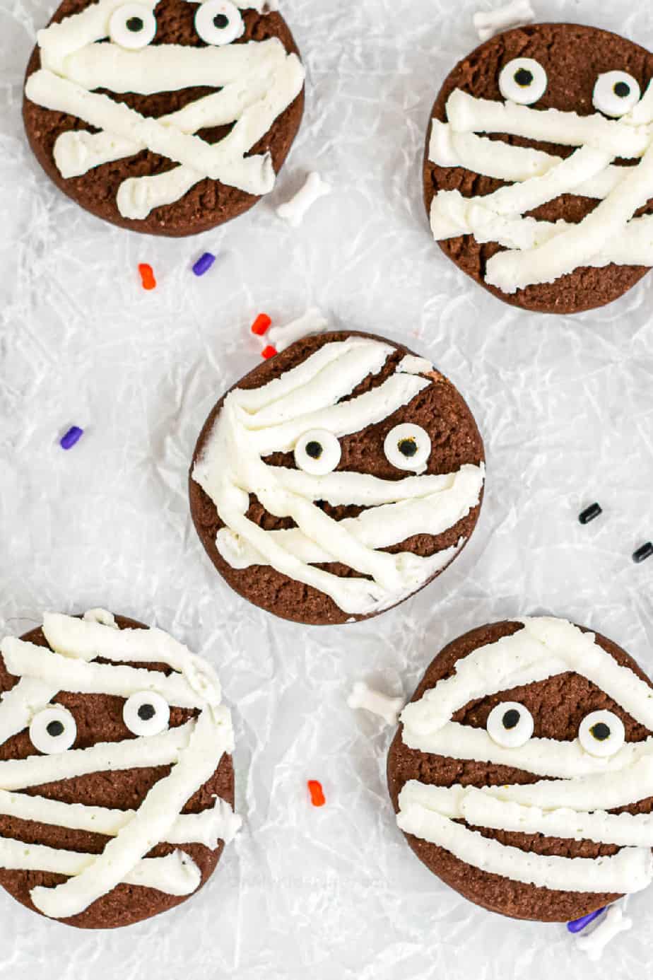 Close up picture of five chocolate cookies decorated with frosting and candy eyes to look like mummies