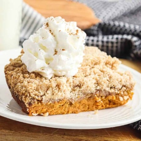 Up close layered pumpkin dump cake topped with whipped cream from the side