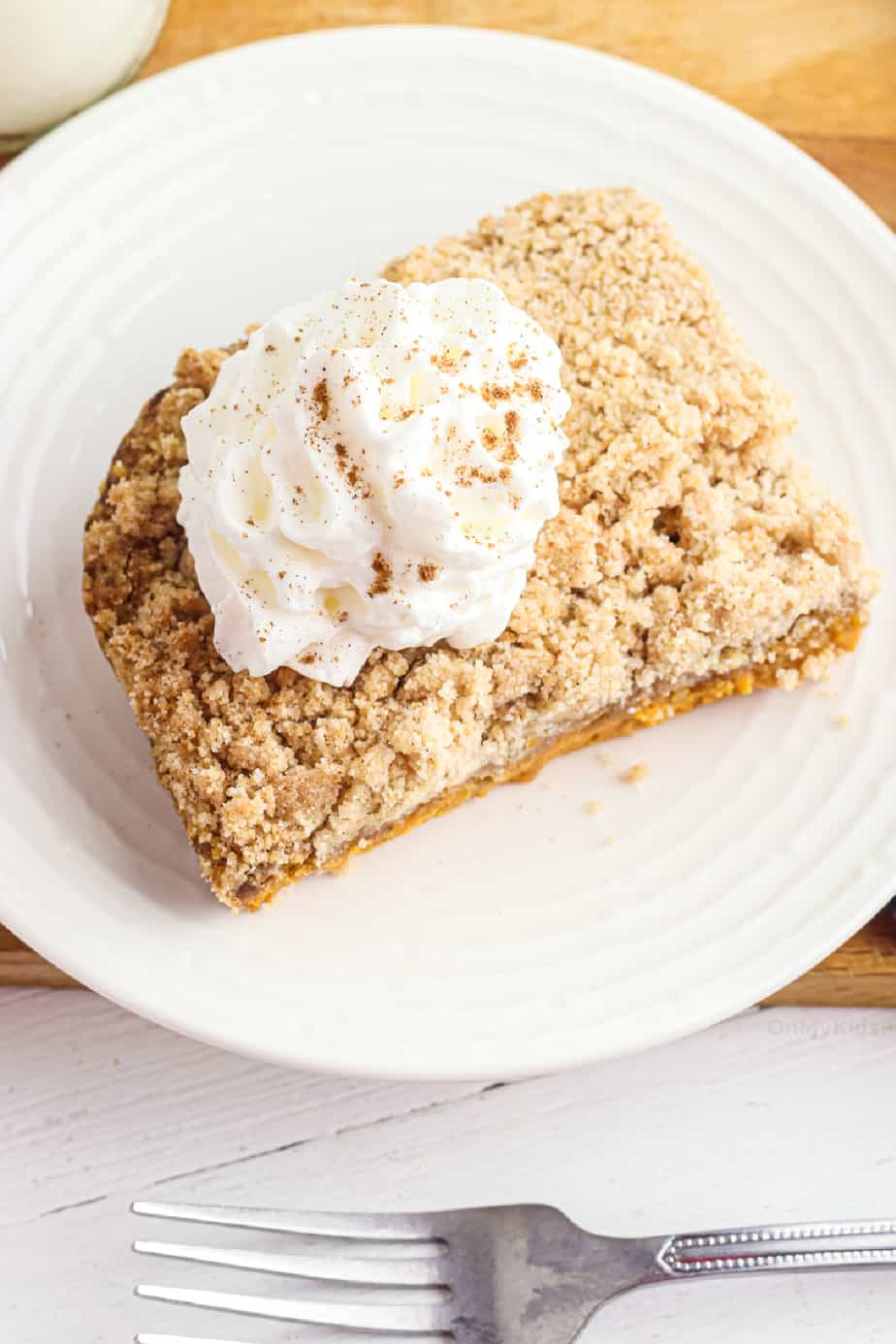 Slice pumpkin cake topped with whipped cream from overhead on a plate with a fork