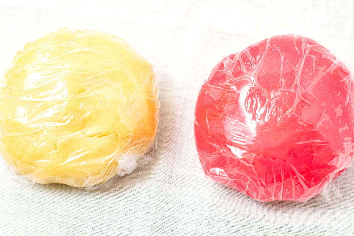 White and red cookie dough balls wrapped in plastic wrap