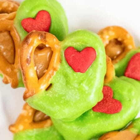 Very close up on several pretzels coated in green chocolate with a red heart