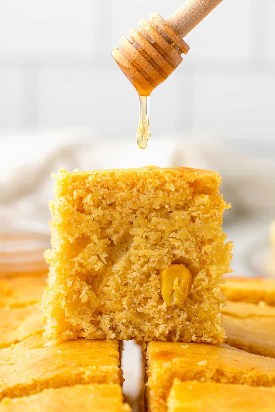 Cornbread stacked with honey being drizzled over the top piece