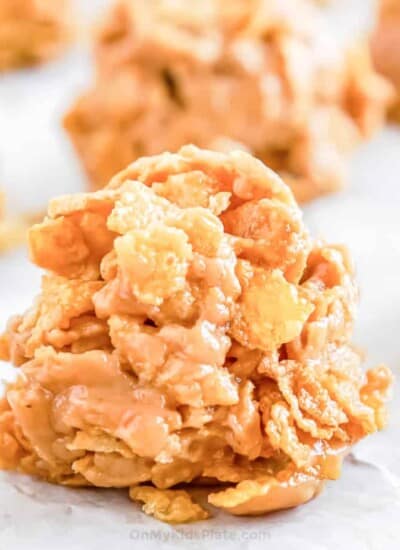 Close up of cornflake no bake cookies on parchment with other cookies in the background