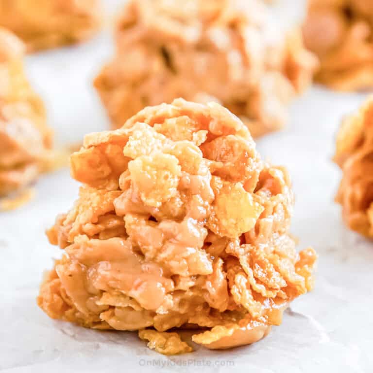 Close up of cornflake no bake cookies on parchment with other cookies in the background