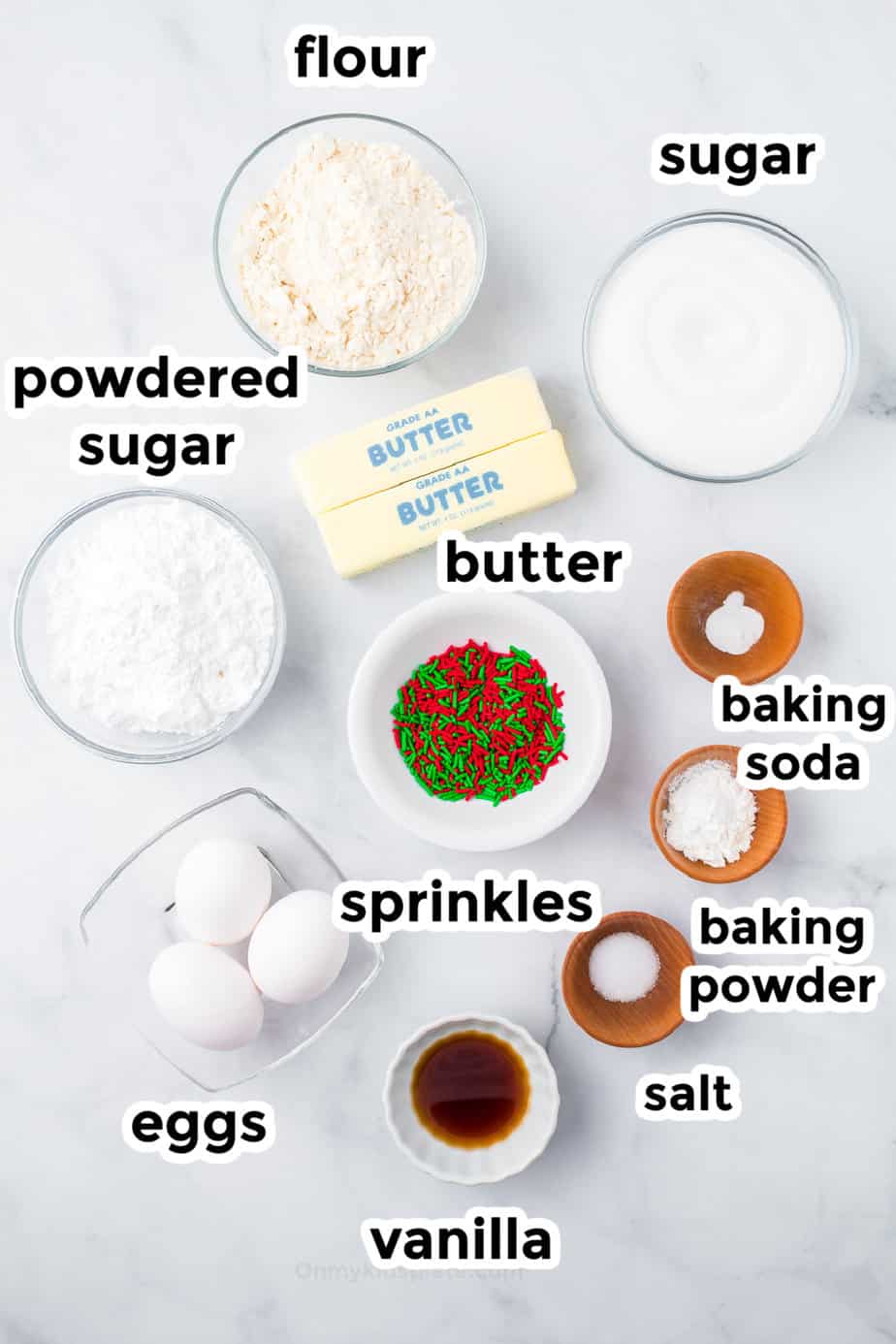 Frosted christmas sugar cookie bar ingredients in bowls from overhead with labels.