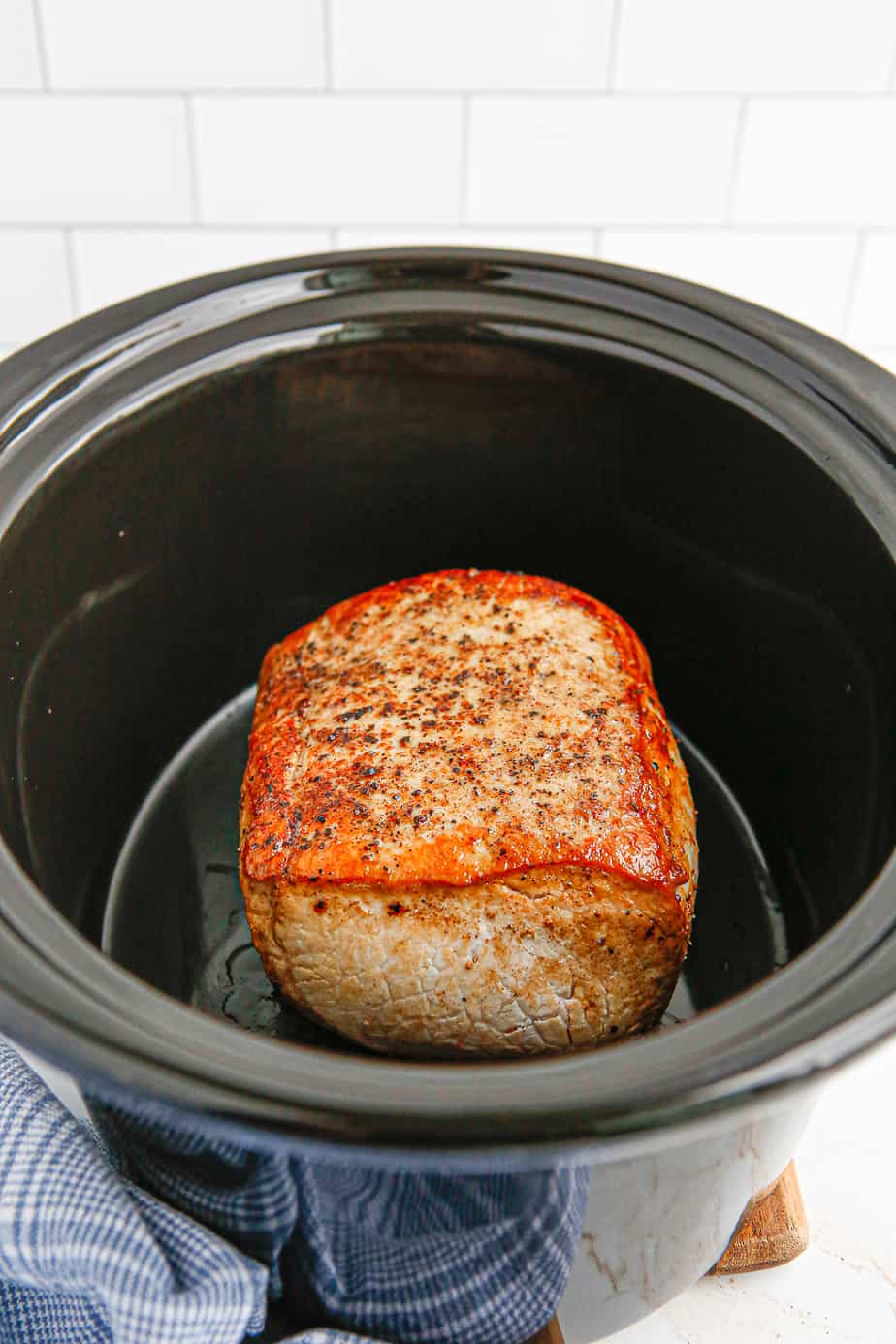 Browned and seasoned pork loin in the slow cooker with the fat side up.
