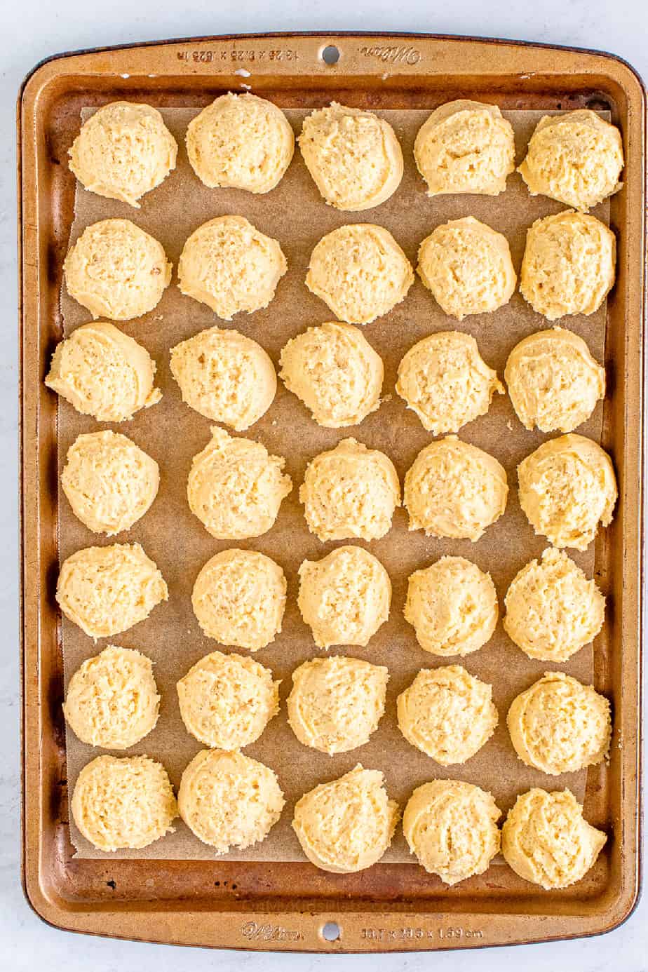 Eggnog cookie dough balls on a baking sheet to refrigerate