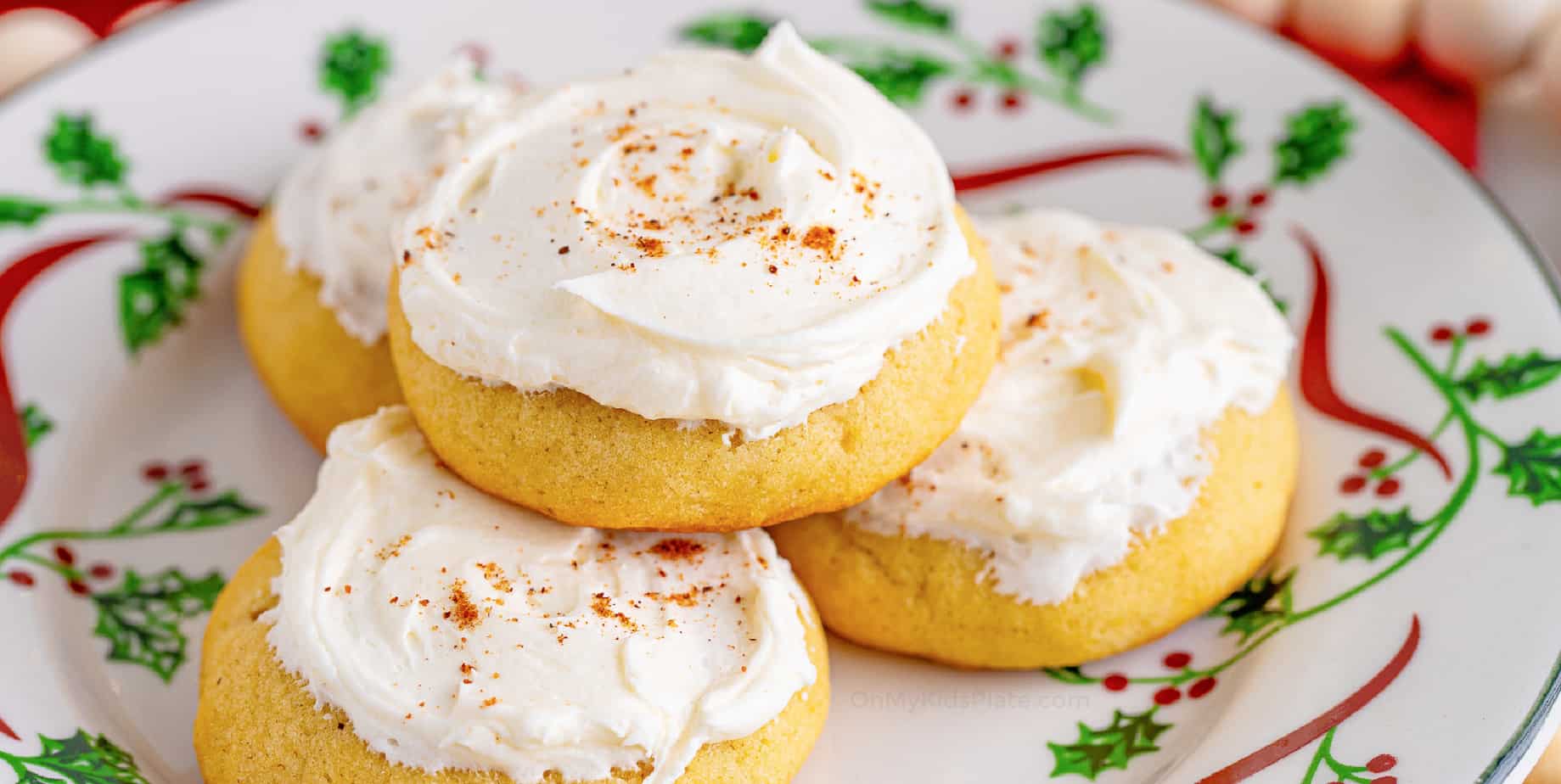 Eggnog cookies frosted and stacked on a plate from the side