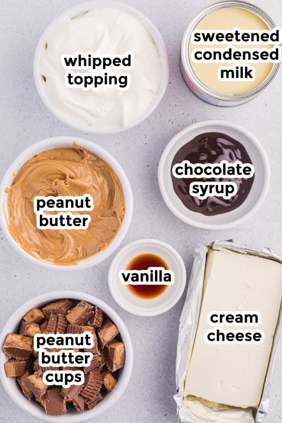 Ingredients for peanut butter cheesecake dip in bowls with text labels