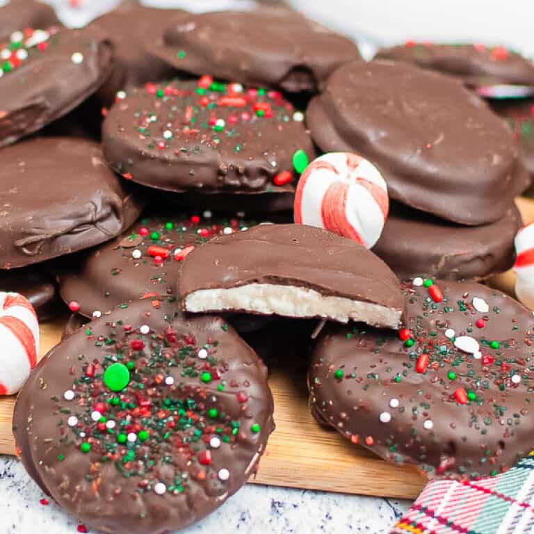 Close up of a stack of peppermint patties stacked on a cutting board with one with a bite