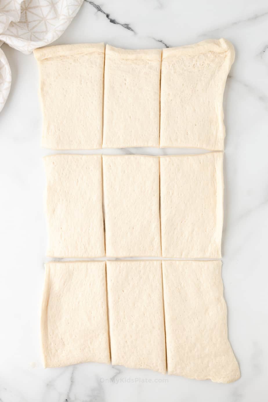 Pizza dough stretched into a rectangle and cut into nine smaller rectangles