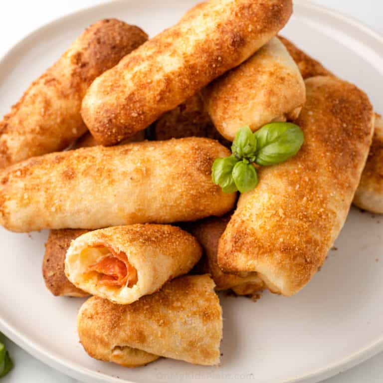 Pepperoni rolls stacked on a plate with one cut in half to see inside